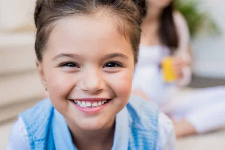 Closeup shot of a little girl smiling and looking into camera.