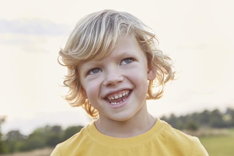 Portrait of blond-haired, blue-eyed boy on playing field