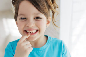 Smiling little girl pointing to her chipped front tooth