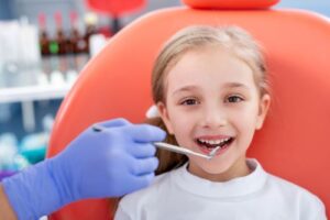 a smiling girl being examined by dental hygienist