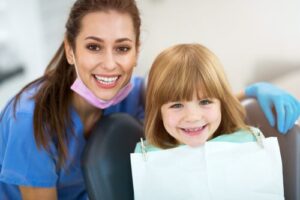 a dental hygienist smiling with a pediatric patient 